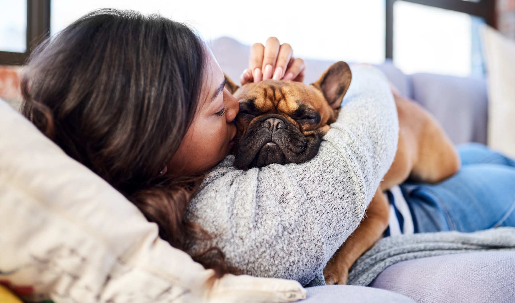 We love our furry friends a woman and a dog laying on a couch